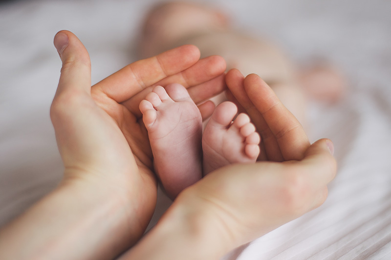 Mani che accolgono i piedi di un neonato